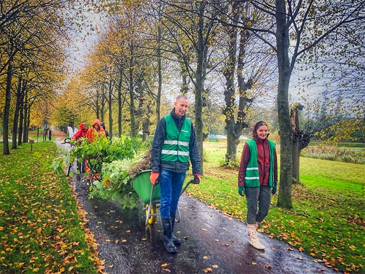 Mensen lopen door een bomenlaan met kruiwagens vol zaailingen